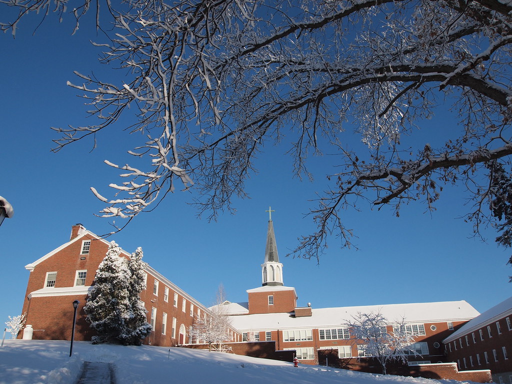 A red brick church with a steeple on the snow-covered grounds of Boston College. 