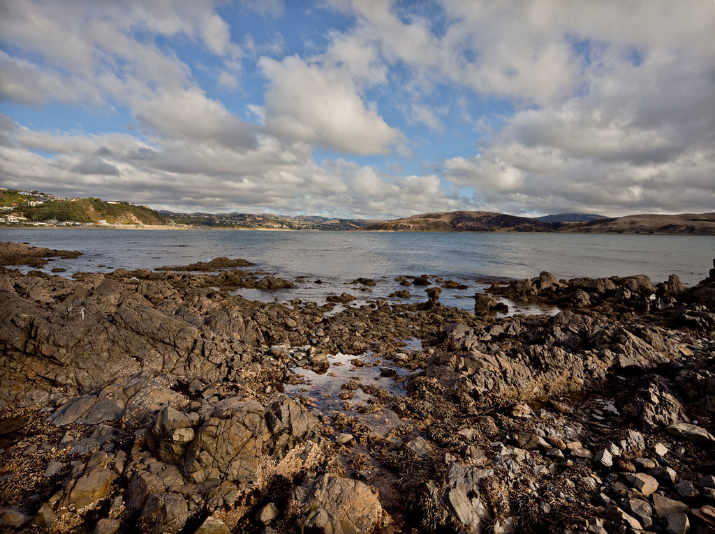 rock pool, hills, village, and cloudy sky by Lester Ralph Blair