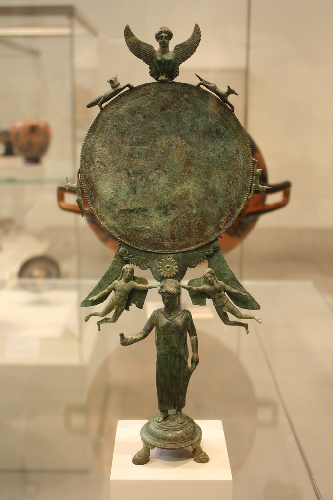 A Magnificent and Important Greek Early Classical Bronze Mirror, the Handle in the Form of a Woman Surmounting Base with Three Bovine Feet