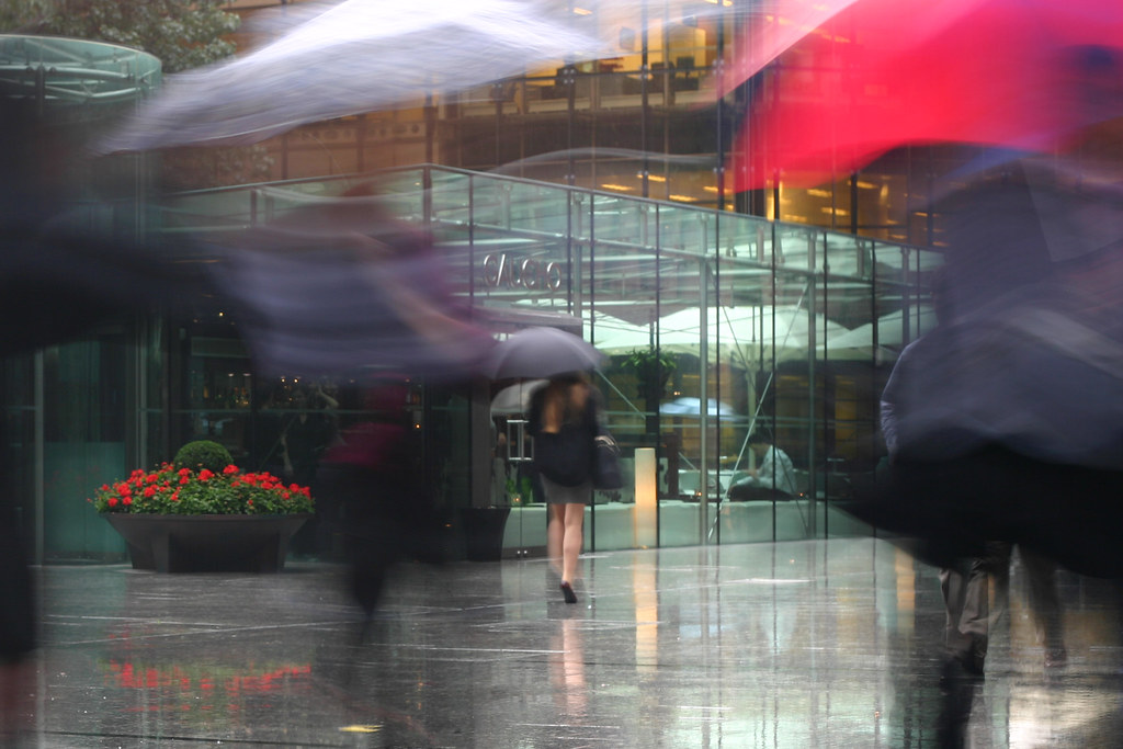 People with umbrellas crossing a rainy city street