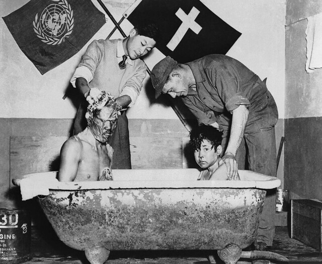 Men wash a pair of war orphan brothers in Korea, the boy on the left has been blind since birth, the UN set up orphanages to help alleviate some of the misery, 1952