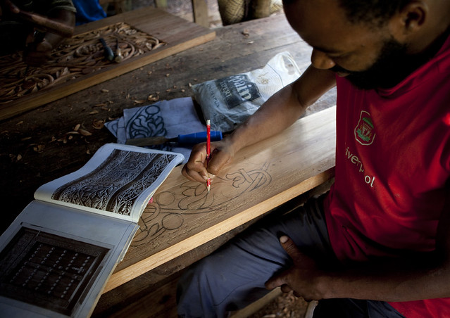 Man drawing patterns on a door in his workshop, Zanzibar, Tanzania