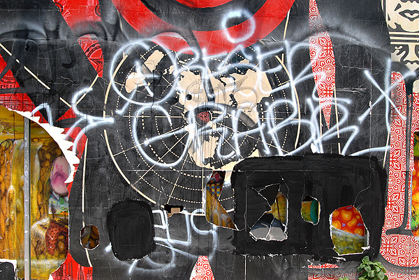 Graffiti and holes punched in the Shepard Fairey Mural on the Bowery and Houston Street in NYC. Photo taken June 27, 2010.  Graffiti by Obese and Grabr. Also FTV.