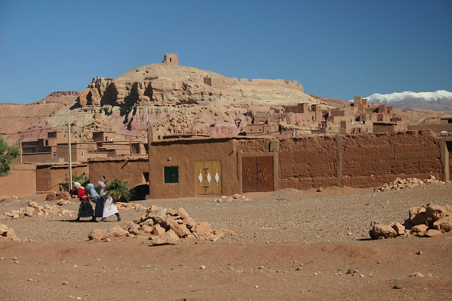 Aït Benhaddou kasbah, snowcapped mountains and berber women carrying firewood