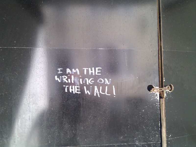 metalic wall chained closed that reads "I AM THE WRiting ON THE WALL"