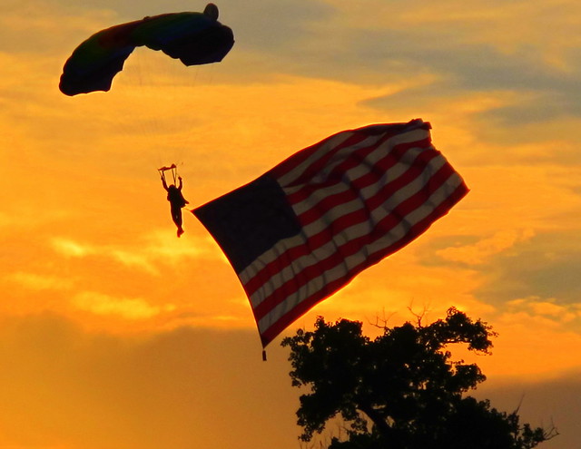 July 4th 2010 Fireworks show with skydiver landing at sunset with American Flag in Austin, Texas, USA