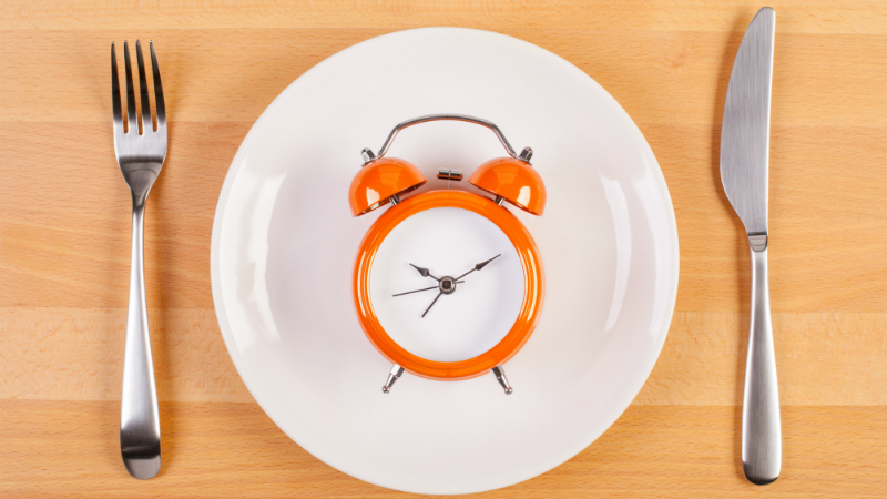 A plate with an alarm clock on it, and a knife and fork either side.