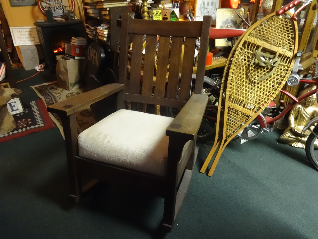 Gustave Stickley Rocker: A dark wood rocking chair with a white cushioin. 