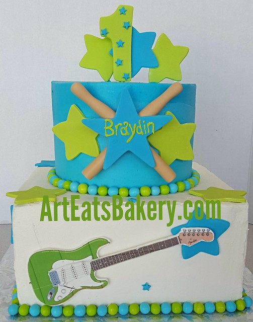 Rock and Roll musician themed buttercream birthday cake with edible number 1, stars, drumsticks and guitar. Http://www.arteatsbakery.com  #cake #guitar #firstbirthday #music #greenvillesc #greenville