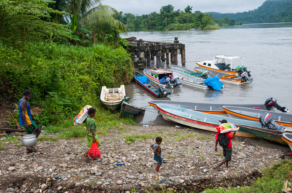 Local residents transport goods into a small boat at the dock. Kasonaweja, Mamberamo Raya, Papua.