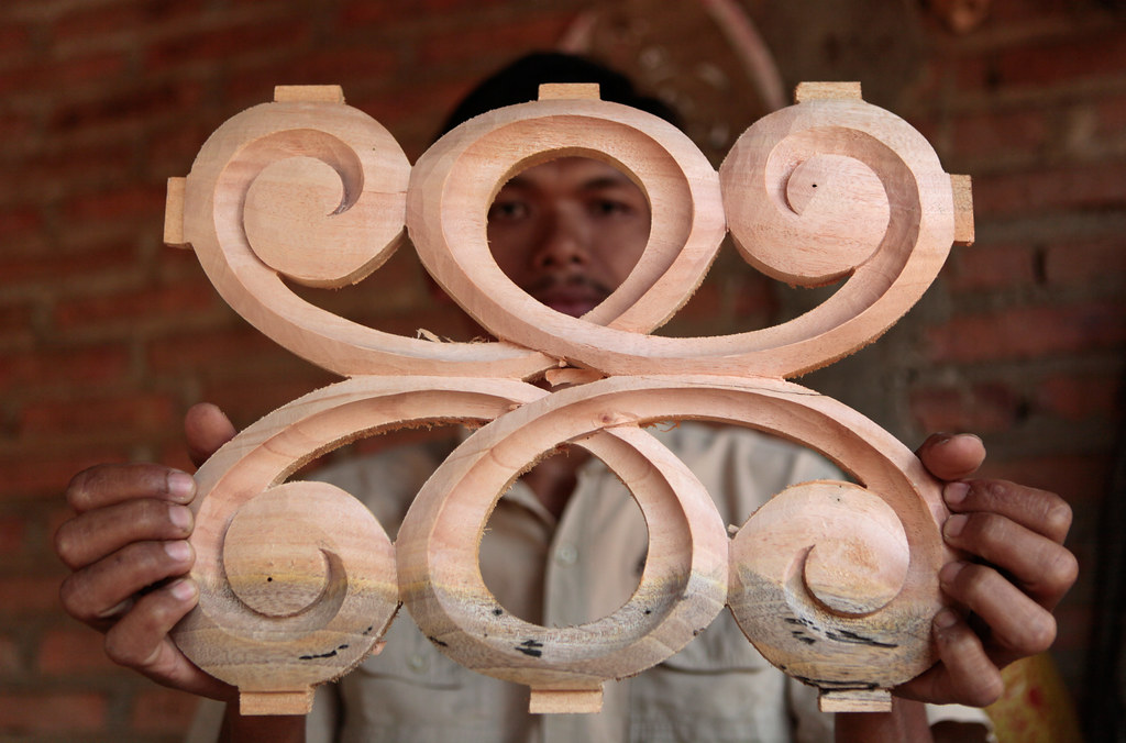A male worker displays a carving before it is assembled into the final piece. Jepara, Central Java, Indonesia. July 2012.