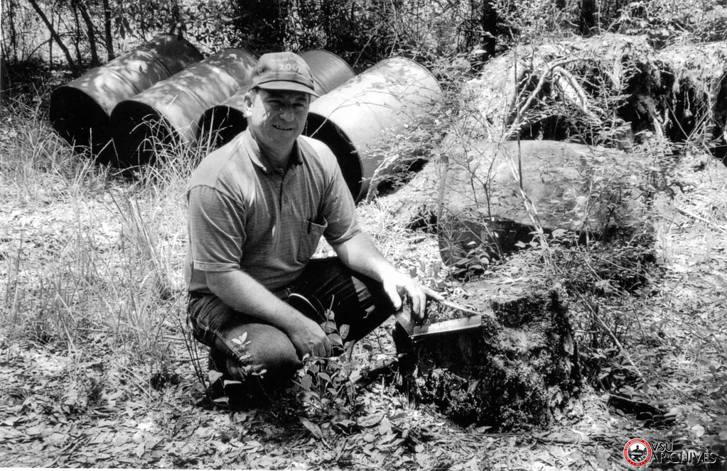 George Music, Jr., of Waycross still works some trees on the family property. Here he poses by the stump of one of the first trees he worked as a boy. Photo by Tim Prizer, 2002. CP-2002.1. https://flic.kr/p/U4xr6u
