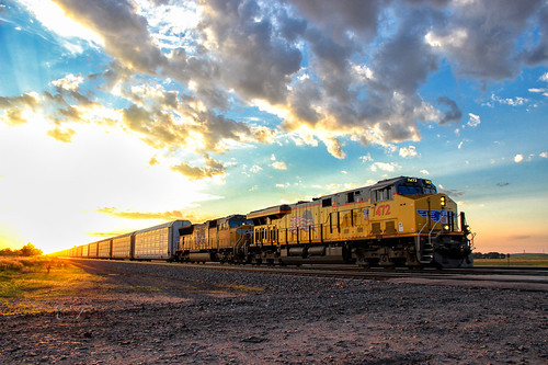Out of the Sun by Carlos Ferran, UP 7472 races east across the high plains on the Kearney Sub, just as the sun sets behind the train