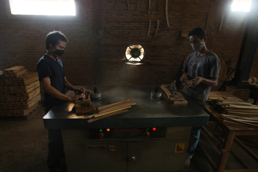 Male workers operating a wood shaper. Japera, Central Java, Indonesia.