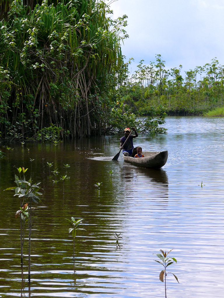 A villager paddles upstream with his son. Papua, Indonesia.
