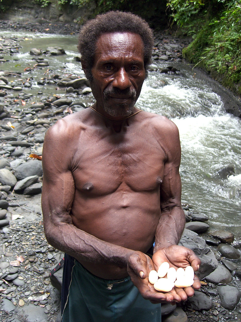 A Papuan man holds white stones. Indonesia.