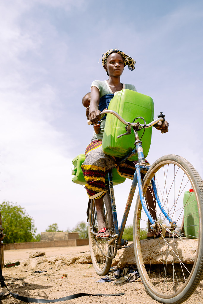 Barry Aliman, 24 years old, rides her bicycle with her baby to collect water for her family, Sorobouly village near...