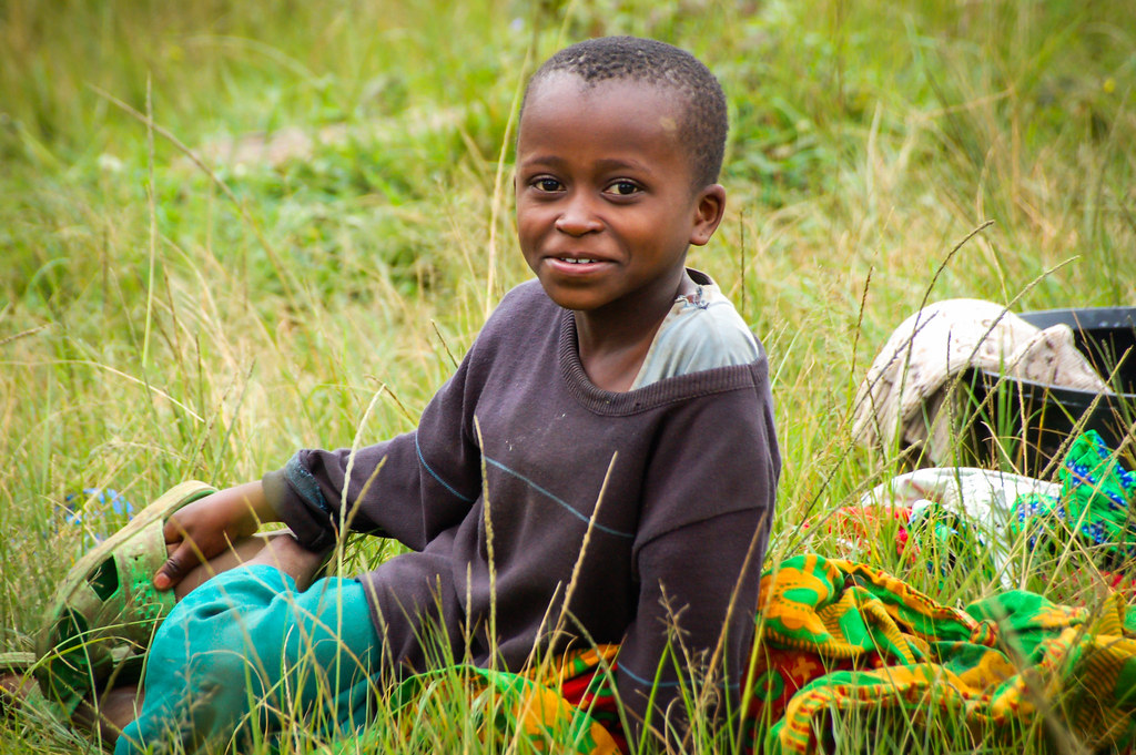 A child sits in the grass. Tanzania.
