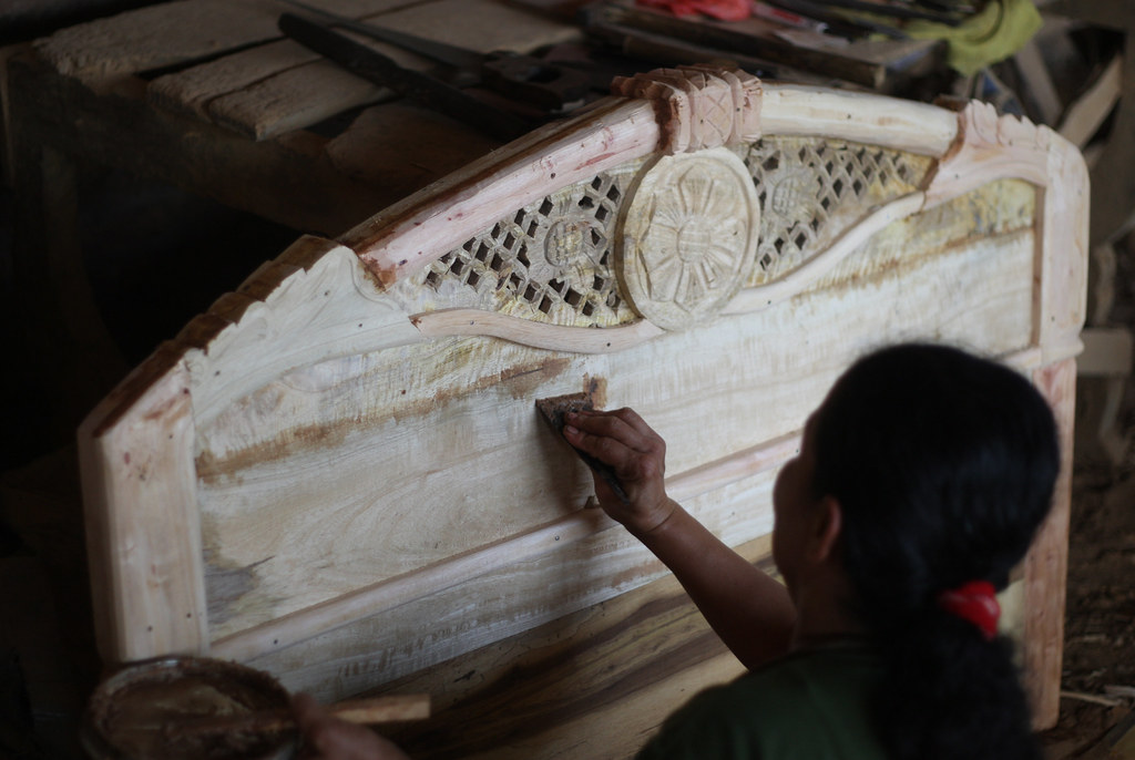 Female worker applies wood filler into any gaps of the assembled piece. Jepara, Central Java, Indonesia. July 2012.