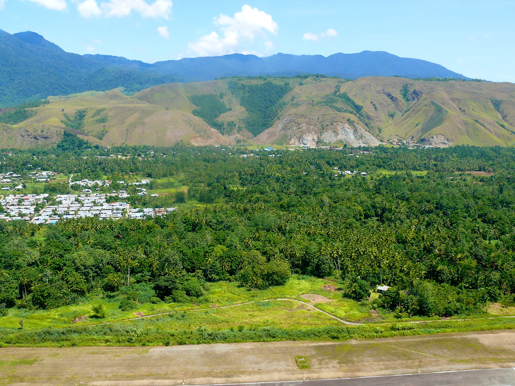 Aerial view, as the plane takes off, of a village nestled between the hills and forest, Papua, Indonesia.