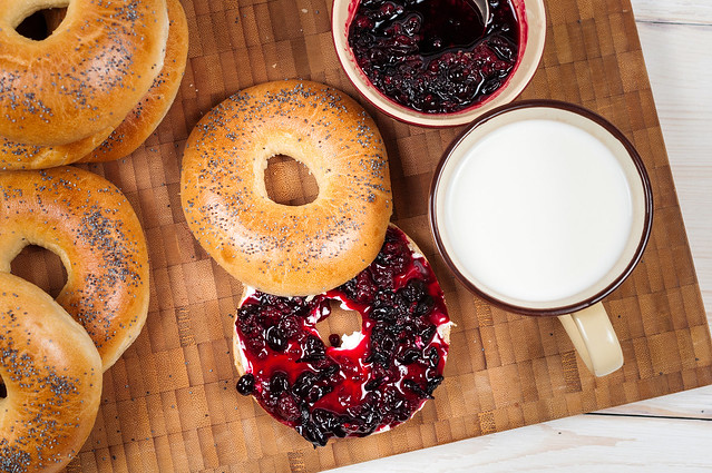 Fresh homemade Poppy bagels bread with cup of milk, cream cheese and berries jam
