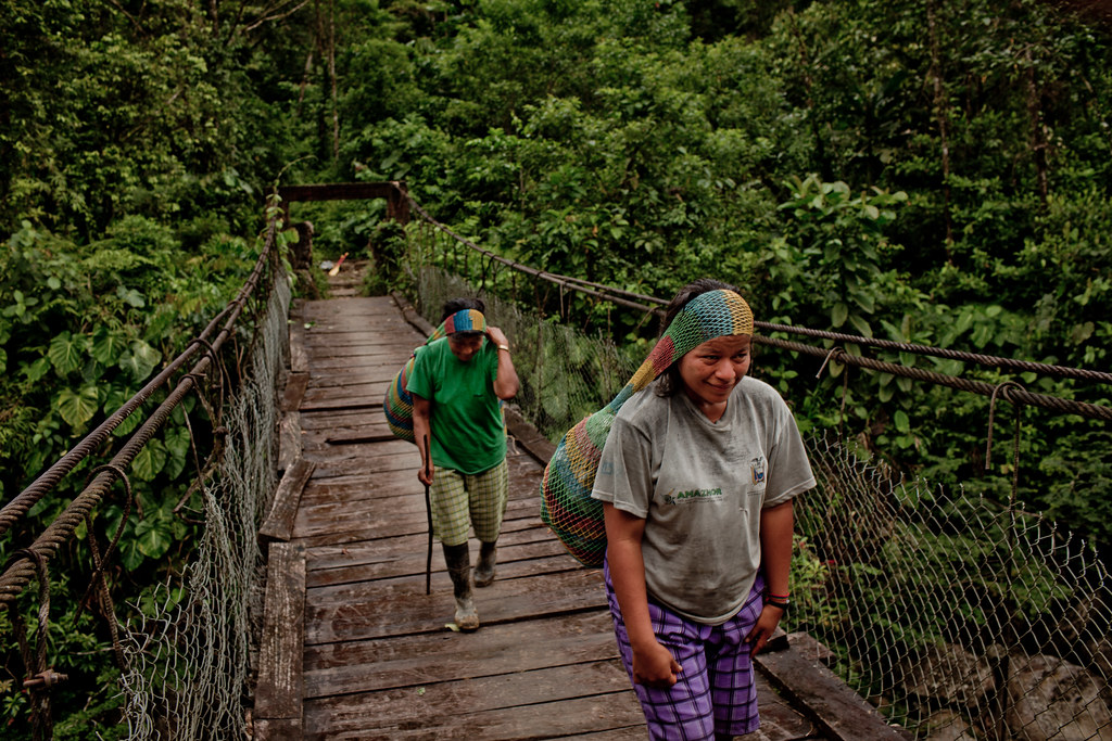 Leaving their oars behind, the Kichwa villagers cross a bridge over the Jondachi river with their bounty, Ecuador.