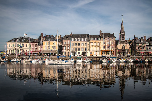 a yacht breaks rich colours of wine-dark summer reflections as it leave the Vieux Bassin (Old Harbour), Honfleur, Calvados, Normandy, France