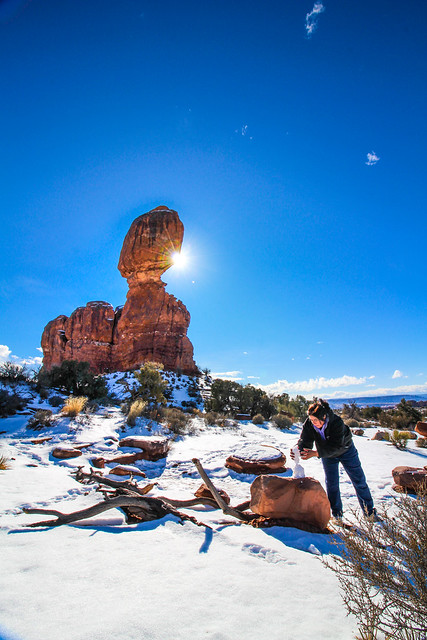 Mom playing in the snow under Balance Rock in Arches National Park, Utah