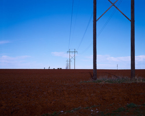 red earth by Tomás Harrison Fotografía, Telephone lines cross freshly plowed red earth under the dying light of the sun on US HWY 380 about