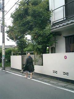 ９：５５ａｍ頃。’鎌倉宮’と金沢街道’岐れ道’との中間。珍しくもない写真だが、笠なし・下駄・こうもり傘で、ビミョーに托鉢僧と異なる。”梅雨時期仕様”なのか？