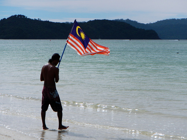 A man waves a Malaysian flag to bring in the seadoos at Langkawi Beach in Malaysia