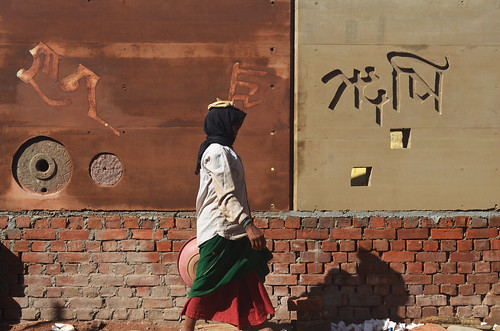 walk rammed earth mason rural india school woman brick wall saree shadow mud