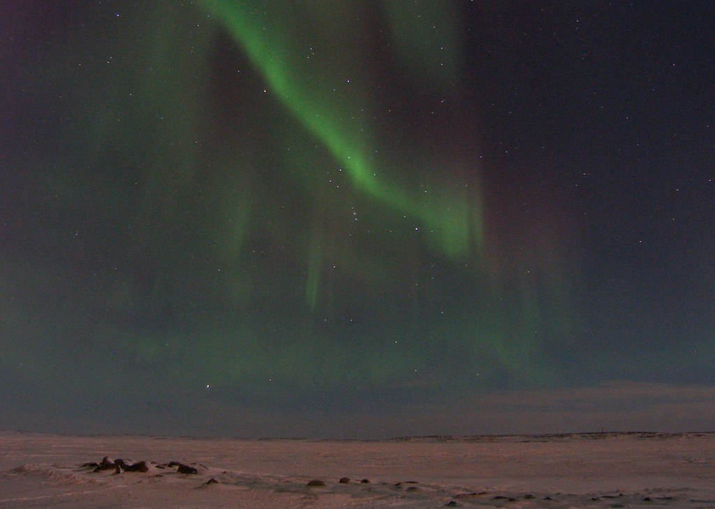 Northern Lights faded over snowy landscape.