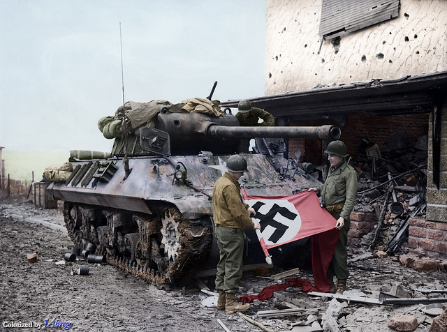 George-Patton's-Third-Army-US-soldiers-roll-up-a-Nazi-flag-they-have-taken-as-a-trophy,-after-the-capture-of-Bitburg,-Feb-1945.Colorized-by-JÁbrego.