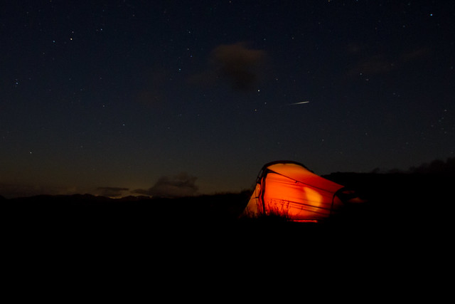 Meteor above glowing tent