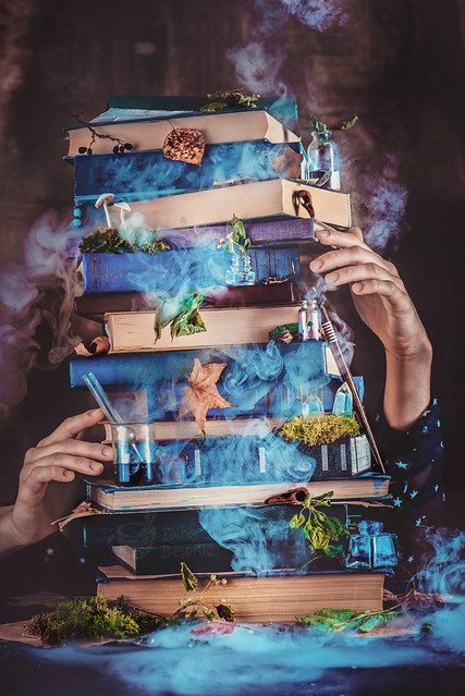 A pile of magical books with wizard hands.