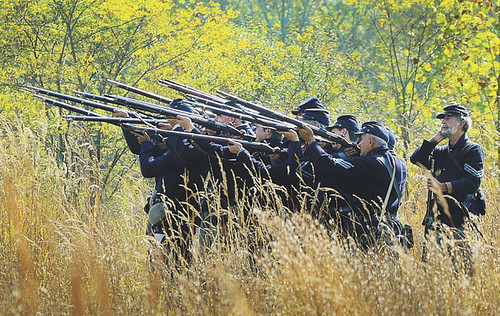 Photo of Civil War re-enactors firing rifles