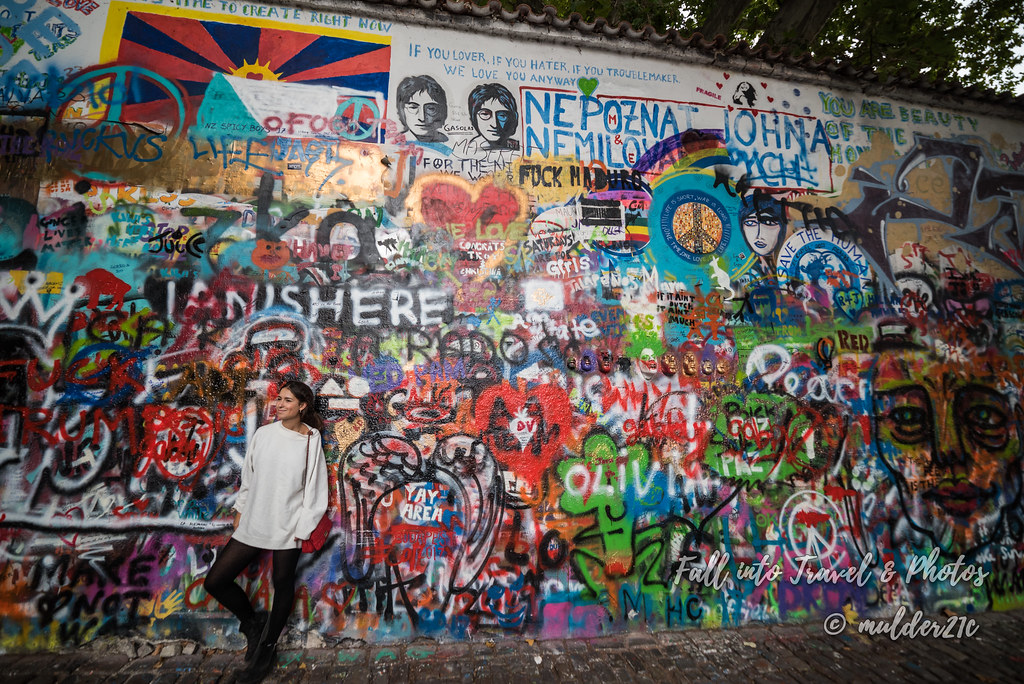 각양각색의 그래피티가 그려진 벽 상단에 존 레논의 얼굴이 그려져 있다