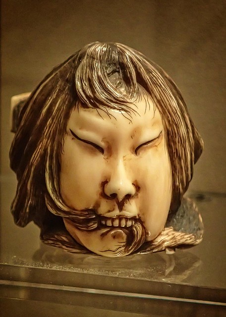 Netsuke miniature of a severed head resting on a dagger by Gyokusai Japan 1800-1900 CE Stained Ivory