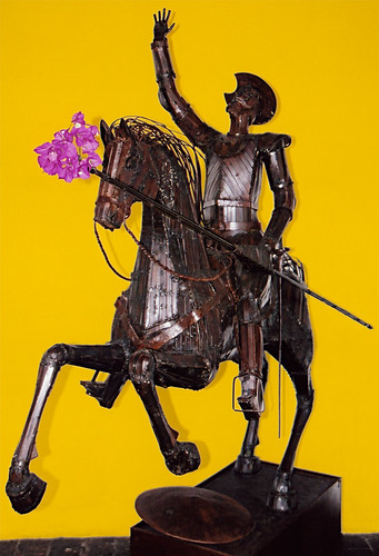 A metal sculpture of the most famous knight, Don Quixote, in Guatemala with a cluster of pink Bougainvillea flowers stuffed on the end of his lance
