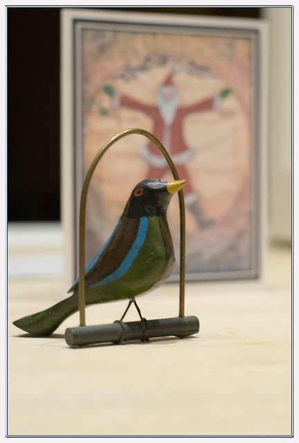 A friend carves wooden Christmas ornaments for his friends and produces his own cards. This year's card is his adaptation of Leonardo's Vitruvian Man seen here behind one of his carved birds.