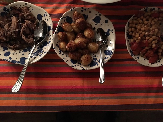 Main in serving plates - lamb, hasselback potatoes, chickpeas and tomatoes