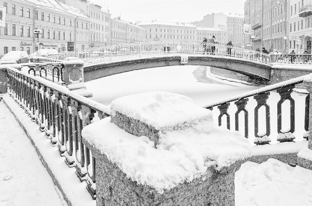 The strong snowstorm in Saint Petersburg. People walking along Sennoy bridge.  B/w image.