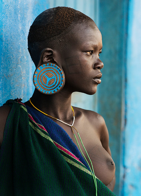A young Suri woman wearing big traditional earrings. It is also traditional for women of this tribe to wear a lip plate although she has opted not to do this. photito travel