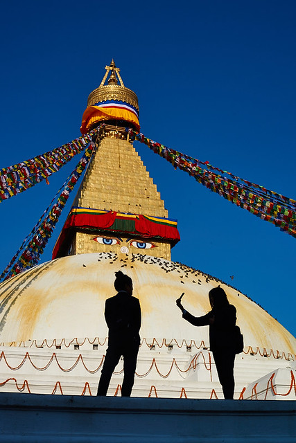 Nepali schoolgirl making selfies in front of the Buddhist stupa of Boudhanath, Kathmandu, Nepal