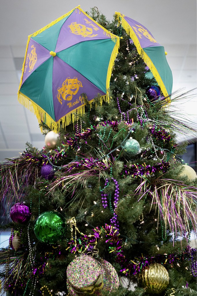 top of a Mardi Gras Christmas tree decorated with purple (…