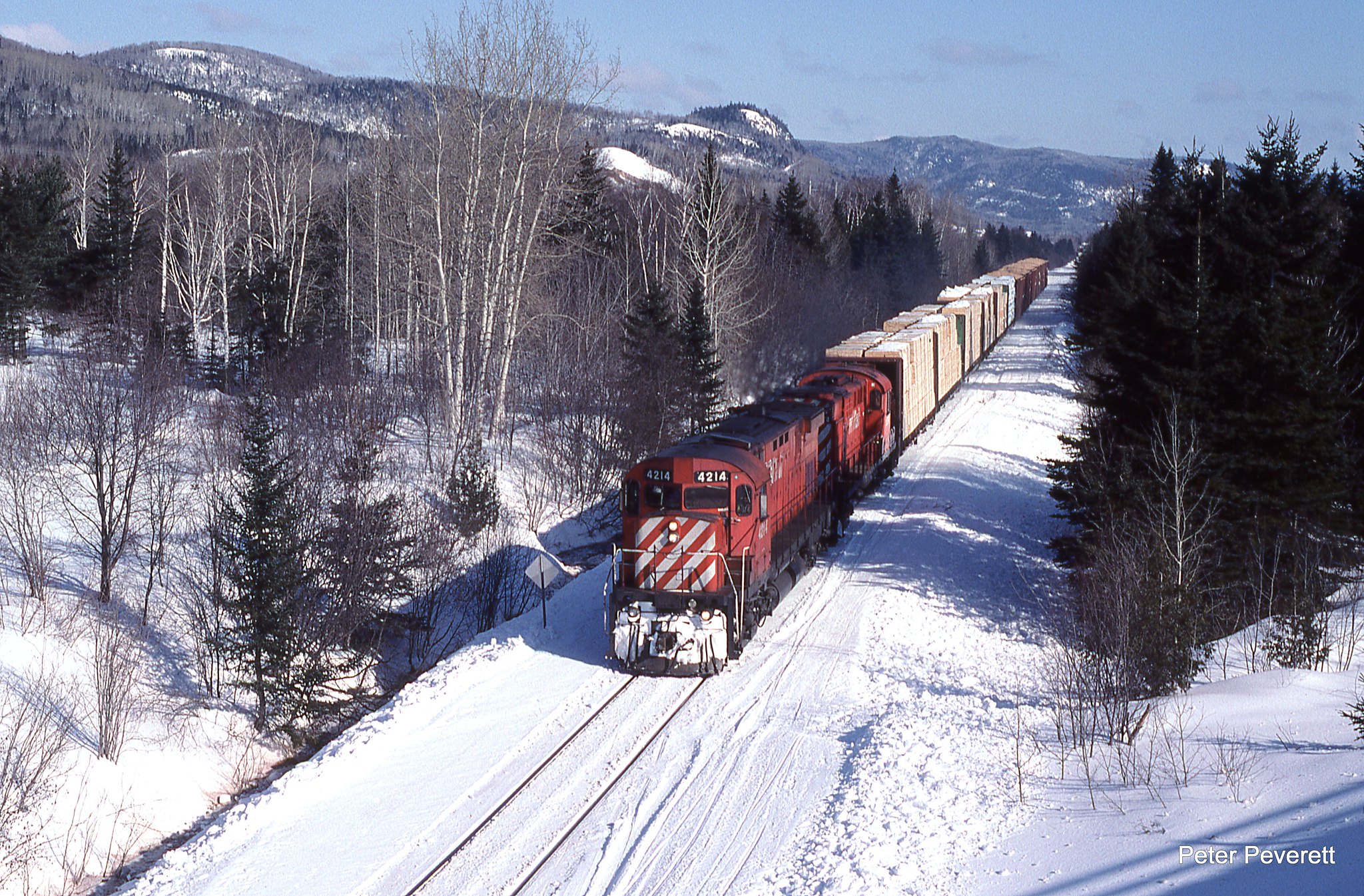 On a very cold day New Brunswick East Coast C-424 # 4214, RS-18 # 1854 are westbound at Pointe-a-la-Croix, Quebec Feb. 10, 2006. The train has a bit of a old school look with un-wrapped lumber headpin from Nouvelle and chips from the shut down mill at New Richmond.  Once the chip pile at New Richmond was cleaned up the freight would terminate at Nouvelle. 