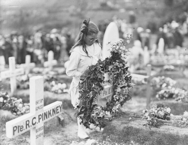 A young girl holding a large wreath at the 2nd Annual Ceremony for Children for placing flowers on the graves of Canadians buried at Shorncliffe Military Cemetery in England, June 23, 1918 / Une jeune fille tient une grande couronne de fleurs à la 2e céré