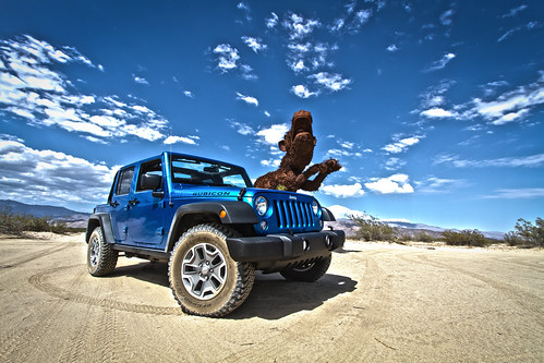 a closeup picture of a blue Jeep wrangler parking in the desert under blue sky