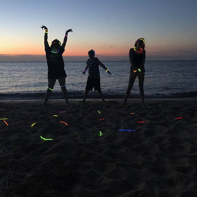 children with glow sticks on the beach at dusk